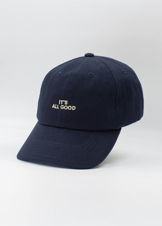 Eine marineblaue Dad Cap von J.Clay mit weißer Stickerei "ITS ALL GOOD" auf der Vorderseite vor einem schlichten, hellen Hintergrund.
