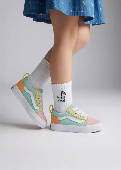 Ein Kind in einem blauen Kleid trägt J.Clay Lama - Mini pastellfarbene Turnschuhe und weiße Lamasocken.