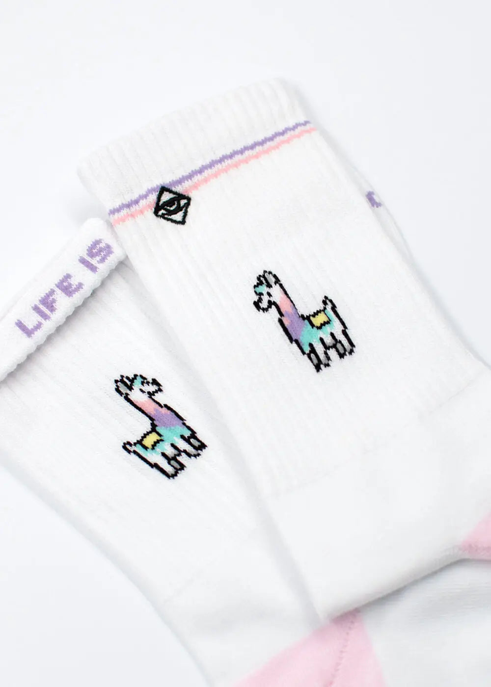 Die J.Clay Lama Socken haben kleine, bunte Lama-Illustrationen und einen lila Streifen am oberen Rand. "LIFE IS" steht in lila auf dem inneren Bündchen. Diese lustigen Socken sind auf einem weißen Hintergrund dargestellt.