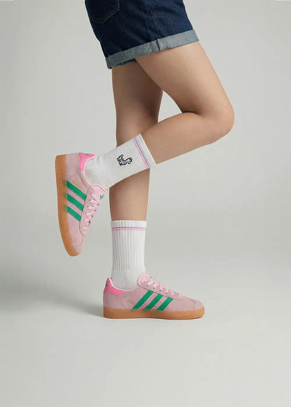 Die Person trägt J.Clay Lama - Kindersocken, rosa Turnschuhe mit grünen Streifen und Denim-Shorts.