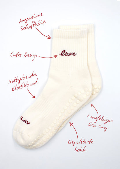 Zwei weiße J.Clay Love Grip Socken mit rotem Text, Pfeilen und hervorgehobenen deutschen Merkmalen.