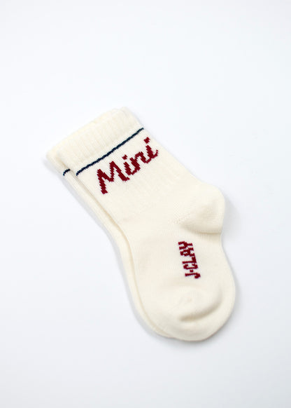 Weiße Babysocke von J.Clay mit rotem Schriftzug "Mini" und einem blauen Streifen am oberen Rand.