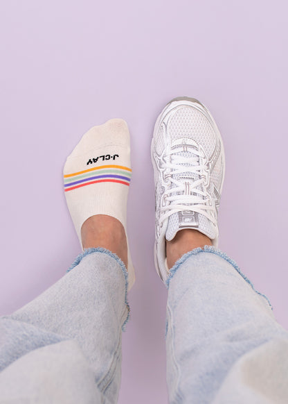 Person in hellen Jeans, ein Fuß in Sneaker Socken, der andere in J.Clay Multi Stripes Füßlinge.