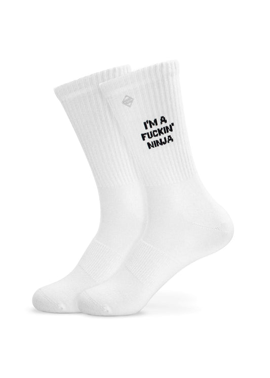 Ein Paar weiße J.Clay Tennissocken mit schwarzem "IM A FUCKIN NINJA"-Schriftzug auf der Seite vor einem schlichten weißen Hintergrund.