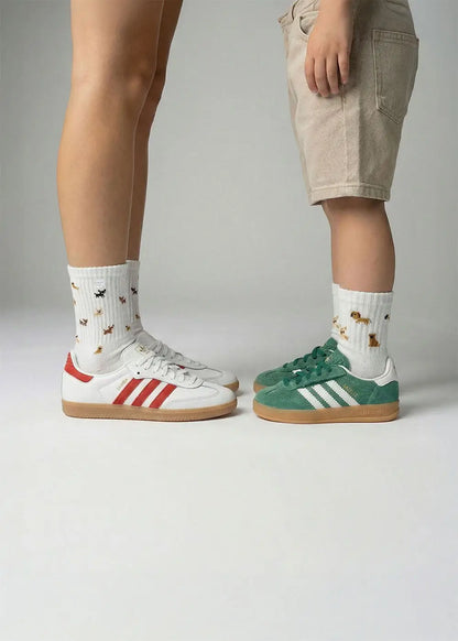 Zwei Personen tragen J.Clay Doggie - Fam Pack Socken, die sich vor einem schlichten Hintergrund gegenüberstehen.