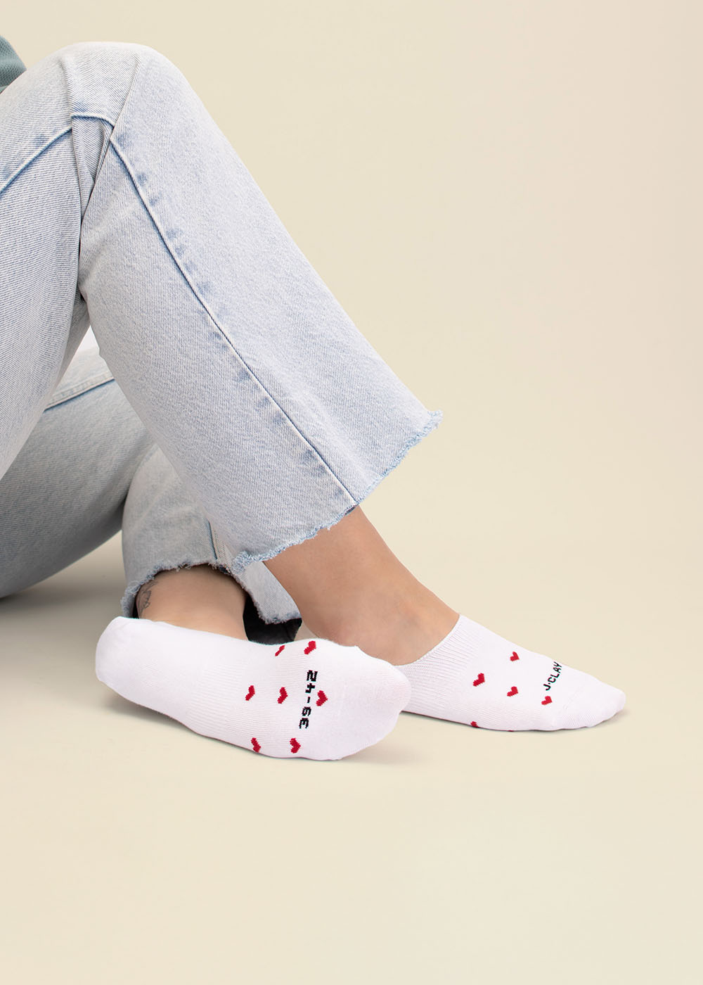 Person in hellen Jeans trägt J.Clay Red Hearts - Füßlinge und sitzt auf dem Boden.