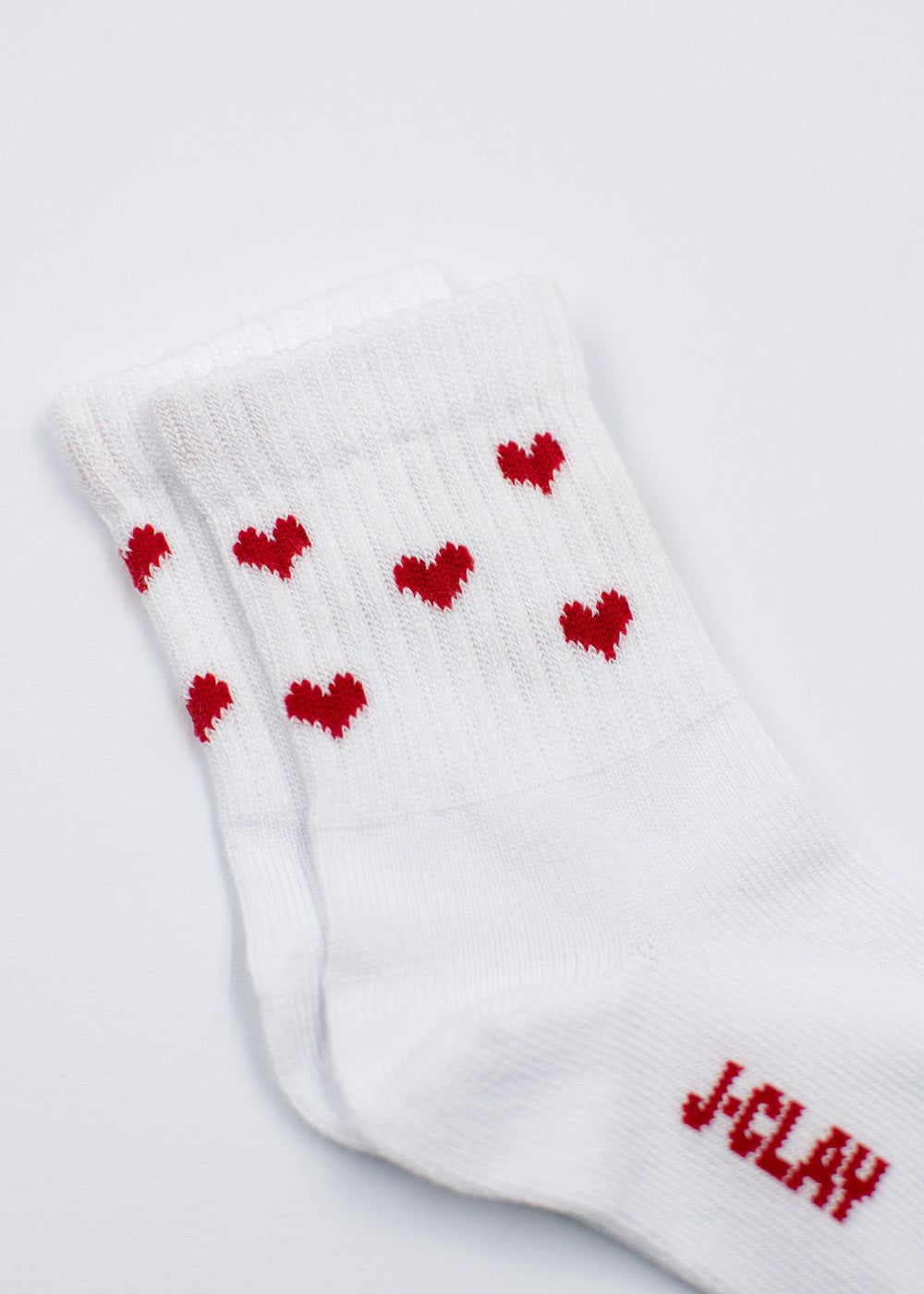 J.Clay Red Hearts – Familienpackung: Weiße Socken mit roten Herzen und dem Schriftzug „JCLAY“ auf einfarbigem Hintergrund.