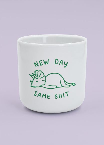 J.Clay New Day – Tasse mit Dino und dem Spruch „new day same shit“ auf helllila Hintergrund.