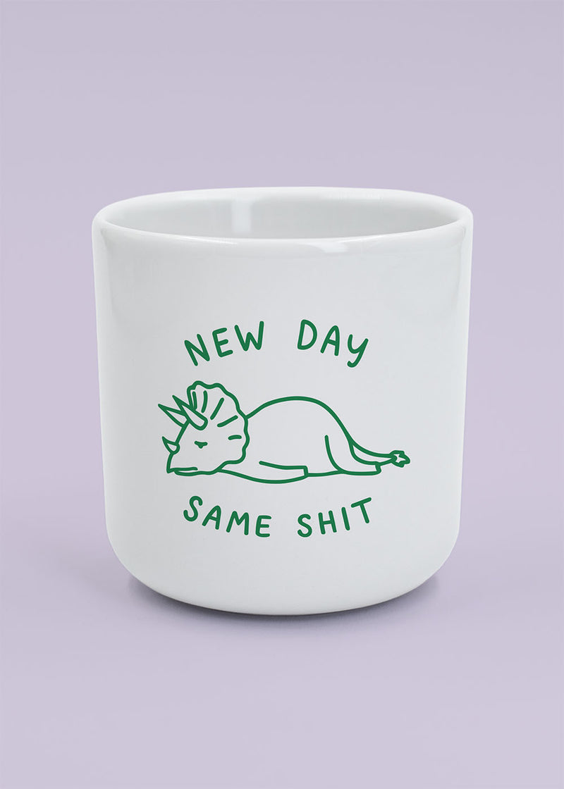 J.Clay New Day – Tasse mit Dino und dem Spruch „new day same shit“ auf helllila Hintergrund.