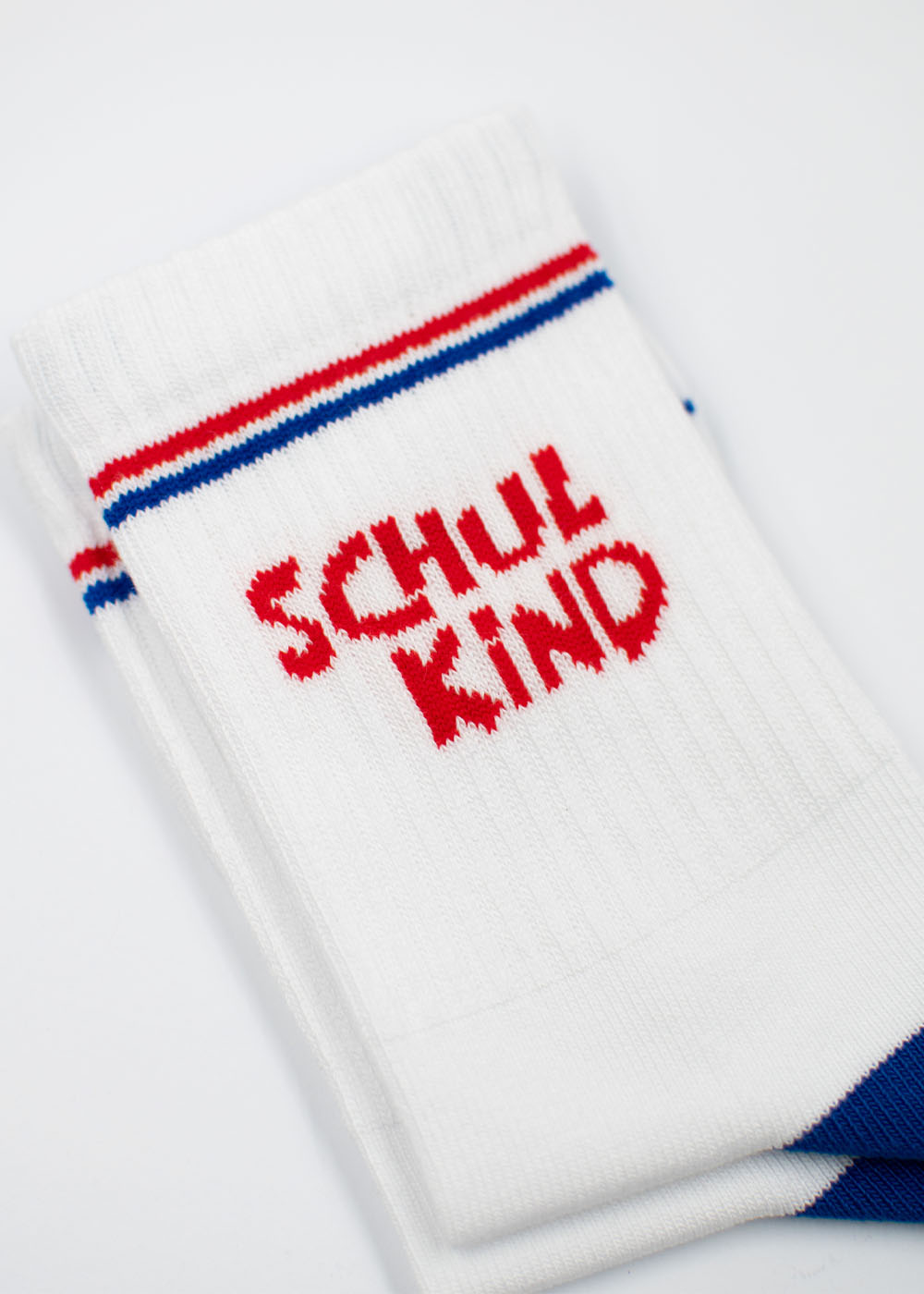 J.Clay Schulkind - Red Blue Kids: weiße Socken mit rot/blauen Streifen und rotem SCHULKIND-Schriftzug.