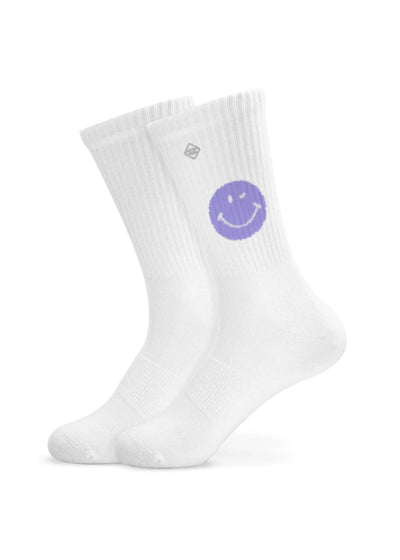 Ein Paar weiße J.Clay Tennissocken mit einem lilafarbenen Smiley an der Spitze und einem kleinen quadratischen Logo über dem Knöchel, die aufrecht auf einem schlichten weißen Hintergrund stehen.
