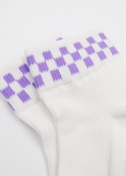 Eine Nahaufnahme der J.Clay Grape Check Sneaker Socken Damen zeigt ein lilafarbenes Karomuster in der Nähe der Bündchen vor einem schlichten weißen Hintergrund.