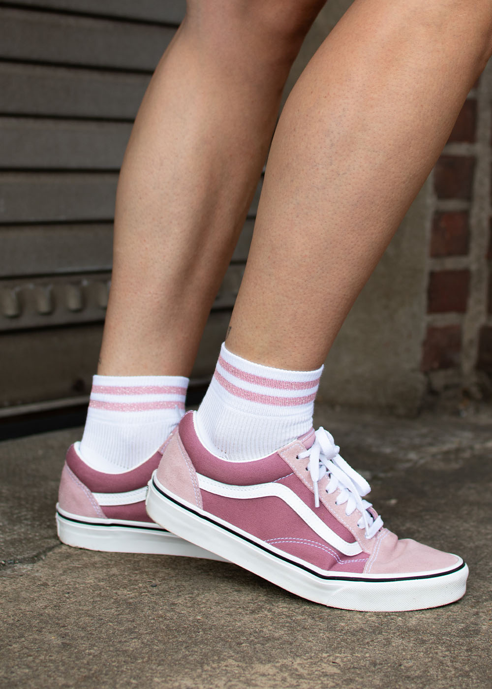 Person in „J.Clay Glitter Stripes“ – SSH-Socken mit rosa Streifen und rosa Sneakers auf Beton.