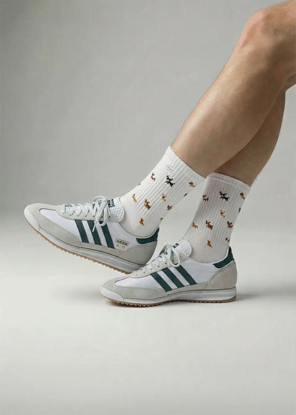 Person in J.Clay Doggy weißen Retro-Turnschuhen und Socken mit süßem orangefarbenem Hundeaufdruck.