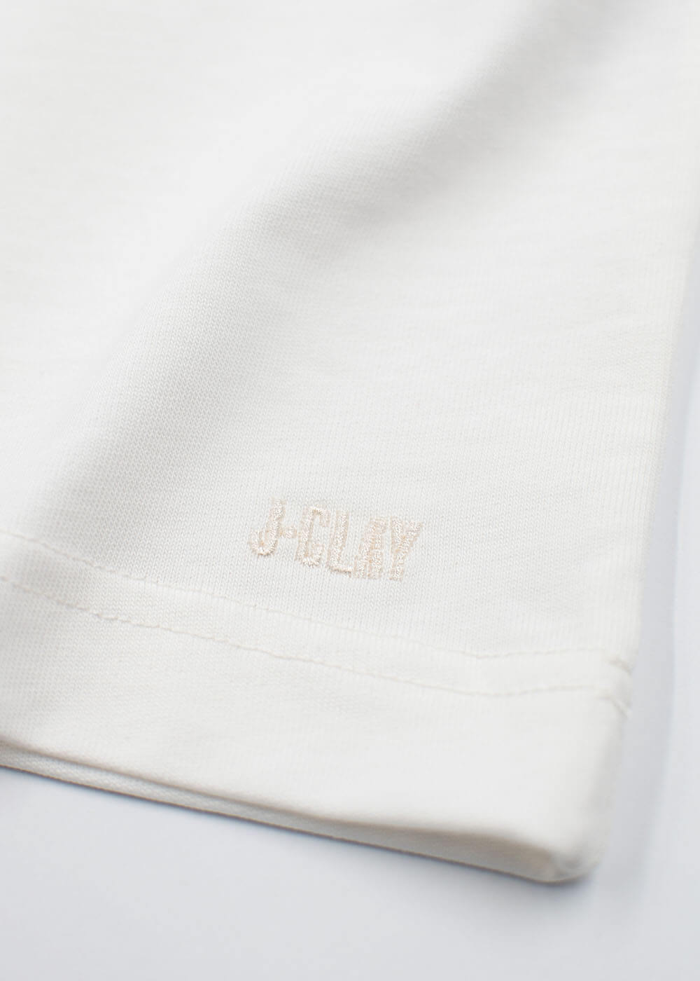 „Close-up of a Good Vino“ – T-Shirt: weißer Stoff mit der Aufschrift „J.Clay“ in Beige am Rand gestickt.