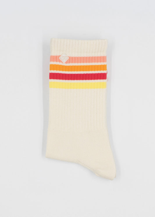 Eine einzelne cremefarbene J.Clay Tennissocke mit horizontalen roten, orangefarbenen und gelben Streifen in der Nähe des oberen Randes, flach auf weißem Hintergrund dargestellt.