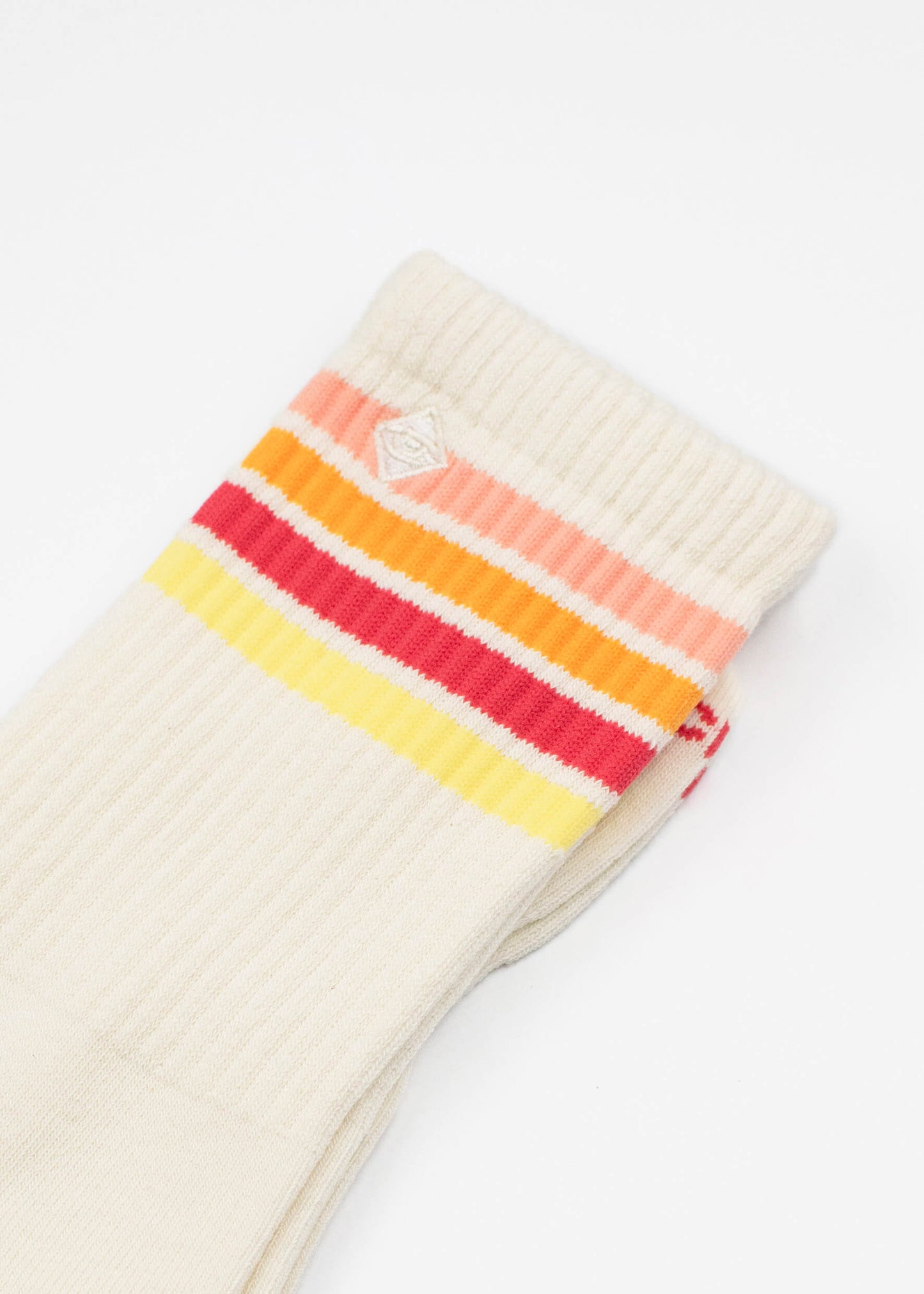 Ein Paar cremefarbene J.Clay Tennissocken mit orangefarbenen, rosafarbenen, roten und gelben horizontalen Streifen in der Nähe der Oberseite auf weißem Hintergrund.