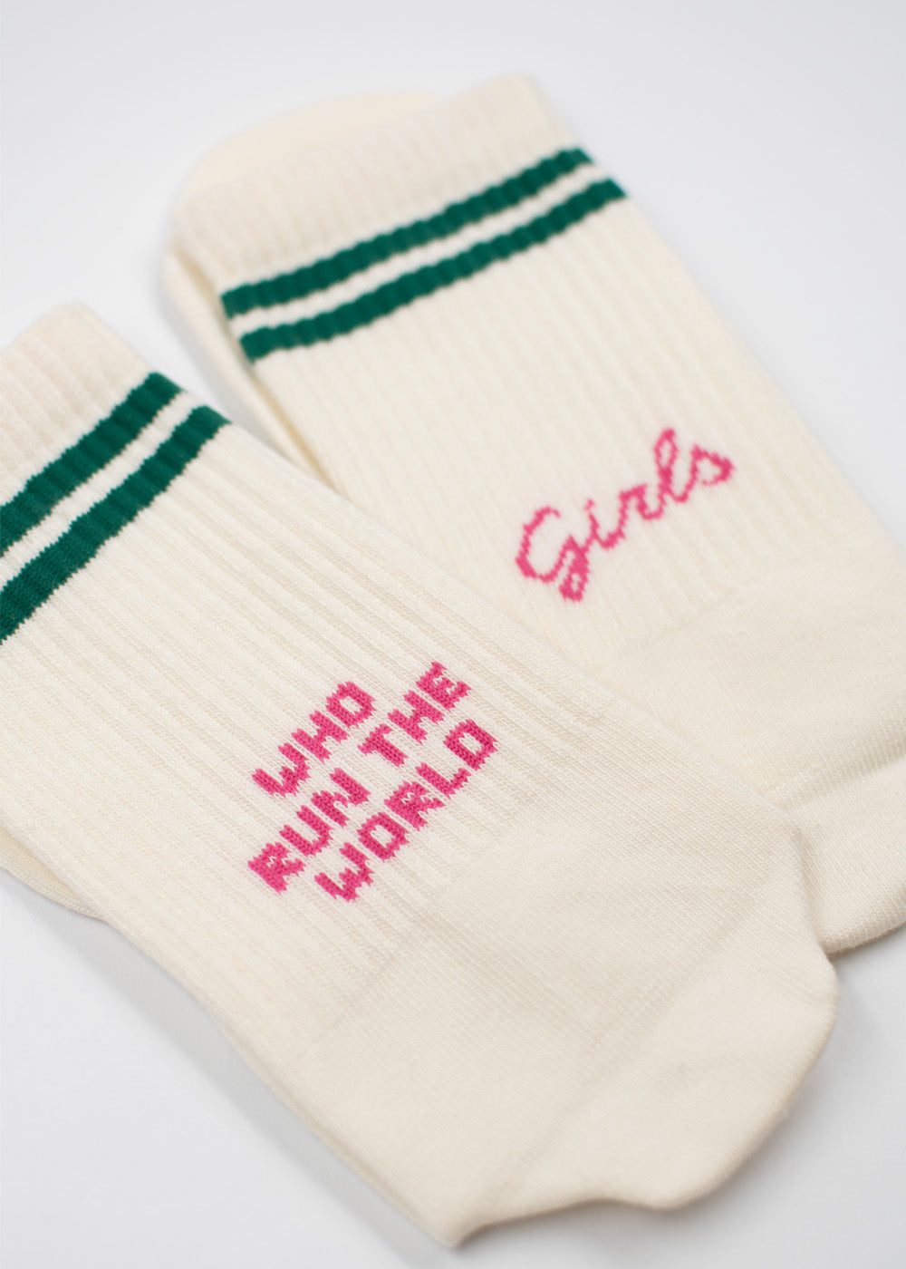 Zwei cremefarbene J.Clay-Socken mit grünen Streifen und dem rosa Schriftzug „Who run the world“.