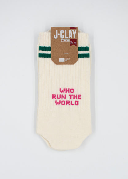 Cremefarbene Socken von J.Clay mit grünen Streifen und dem rosa Schriftzug „WHO RUN THE WORLD“ auf der Vorderseite.