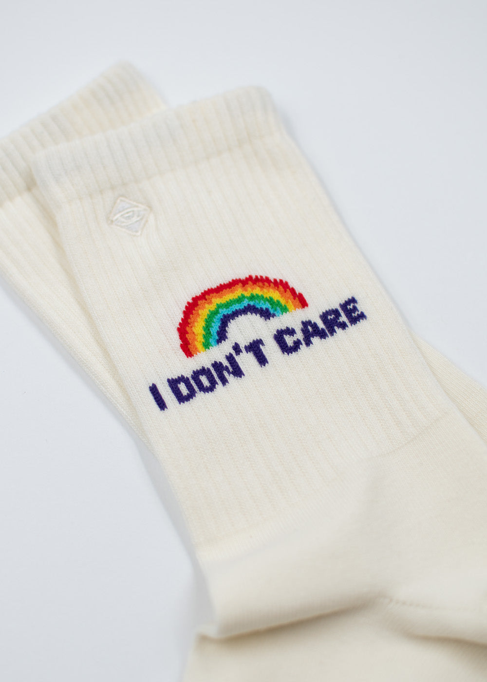 J.Clay „I don’t care“-Tennissocken: cremefarben, mit Regenbogenmotiv, ausgeprägter Streetstyle-Flair.