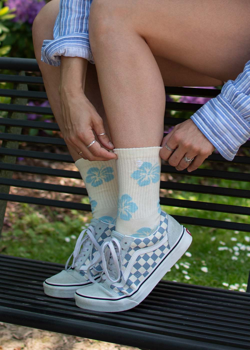 Person, die J.Clay Hibiscus Flower Socken trägt und auf einer Bank im Freien sitzt.