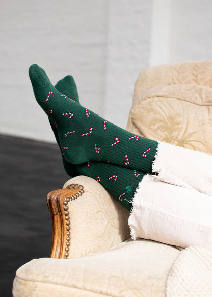 Dunkelgrüne Candy Cane-Weihnachtssocken, die auf einem Sessel liegen.