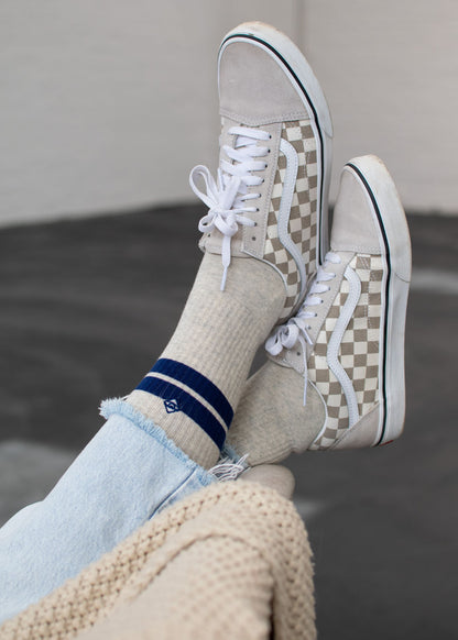 Person, die karierte Sneaker, J.Clay True Stone Navy Tennissocken und hellblaue Jeans trägt.