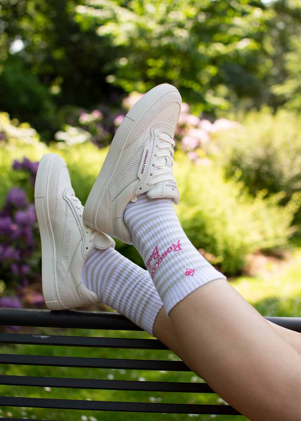 Ich entspanne mich im Garten und trage weiße J.Clay Prosecco Baby Sneakers und gestreifte Retro-Socken.