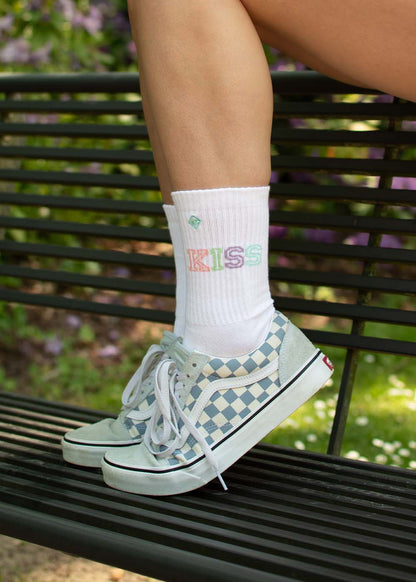 Person mit karierten Turnschuhen und J.Clay Kiss-Socken, einem auffälligen Accessoire, auf einer Bank.