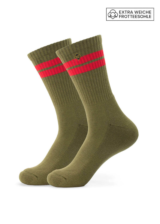 Ein Paar olivgrüne J.Clay Tennissocken mit gerippten Bündchen, zwei roten Streifen im oberen Bereich, einem seitlichen Logo und einem Etikett "EXTRA WEICHE FROTTEESOHLE", das auf extra weiche Frotteesohlen hinweist.