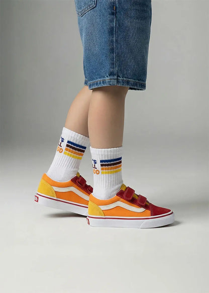 Kind in Jeans-Shorts trägt J.Clay All Good - Mini-Socken und bunte Turnschuhe auf grauem Hintergrund.