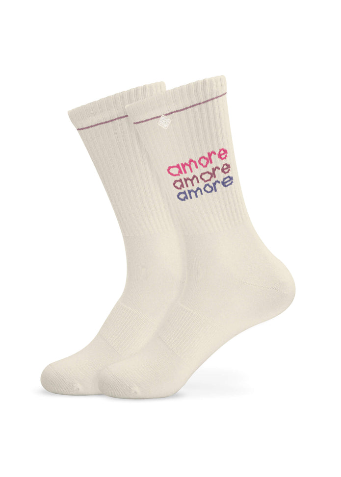 Ein Paar cremefarbene, gerippte J.Clay Tennissocken mit dreifacher Stickerei "amore" in Rot, Rosa und Lila an der Seite und einem dezenten kastanienbraunen Streifen am oberen Rand.