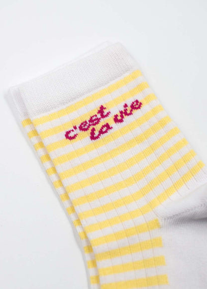J.Clay „c’est la vie“ – Midi: weiße Socke, gelbe Streifen, roter Schriftzug „c’est la vie“ am Knöchel.