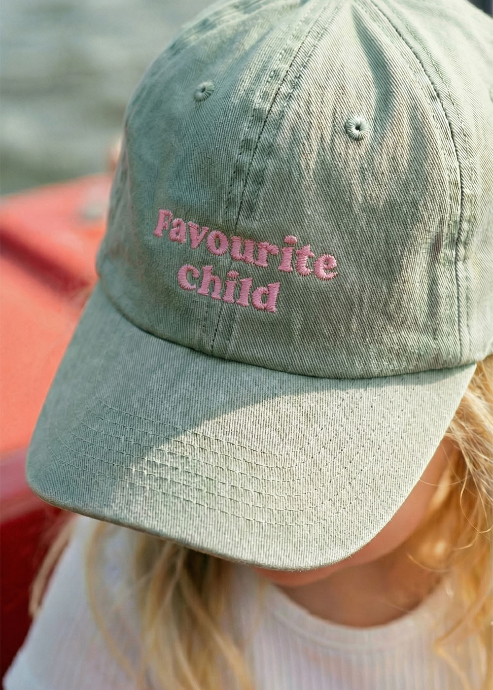 Kind in J.Clay "Favourite Child" Kindermütze mit rosa Stickerei.