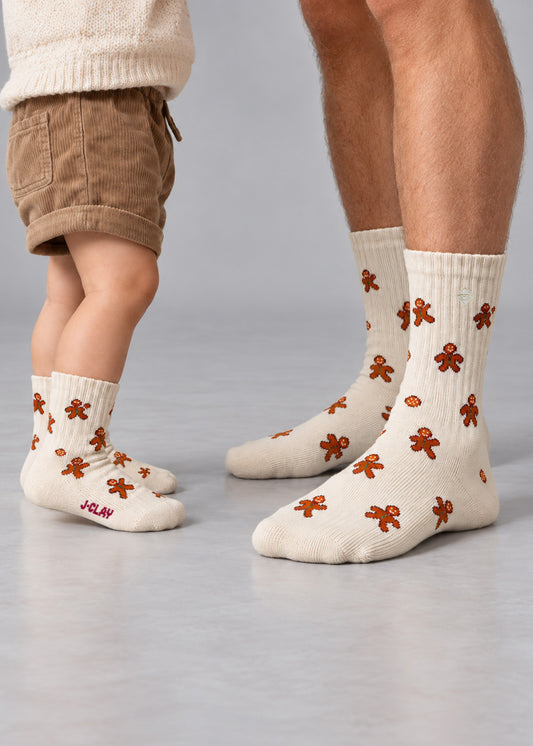 Ein Erwachsener und ein Kind, die beide passende cremefarbene Lebkuchenmann – Fam Pack-Socken tragen.