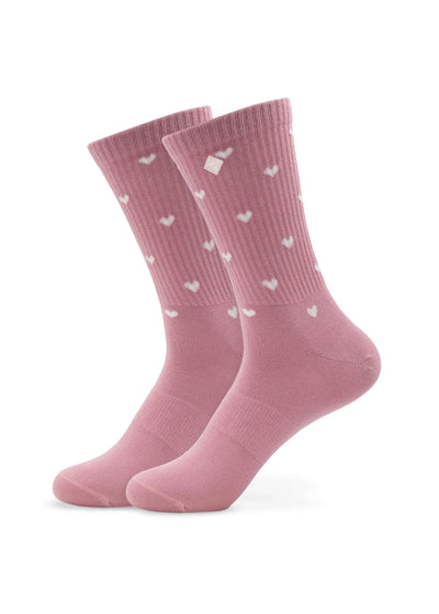 Ein Paar rosafarbene Tennissocken von J.Clay mit kleinen weißen Herzmustern, die aufrecht vor einem weißen Hintergrund stehen.