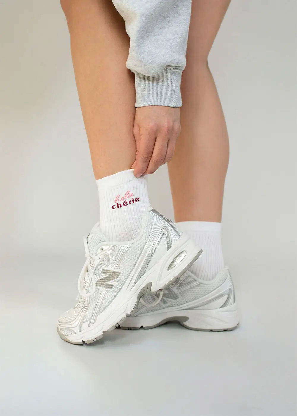 Person in J.Clay Hola Chérie - Midi weiße Socken, graue Jogginghose und weiße Turnschuhe.