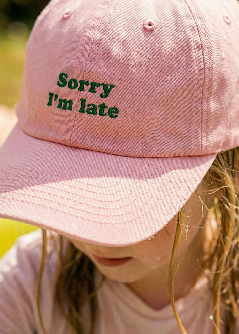 Das Kind trägt eine salbeigrüne J.Clay "Sorry I'm late"-Kindermütze und schaut nach unten.