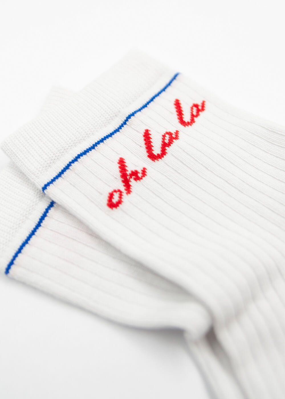 Zwei weiße Baumwollsocken von J.Clay mit blauem Streifen am Schaft und "oh la la" in roter Kursive. Auf weißem Untergrund präsentiert, ideal für Damen, die stylische und bequeme Socken suchen.