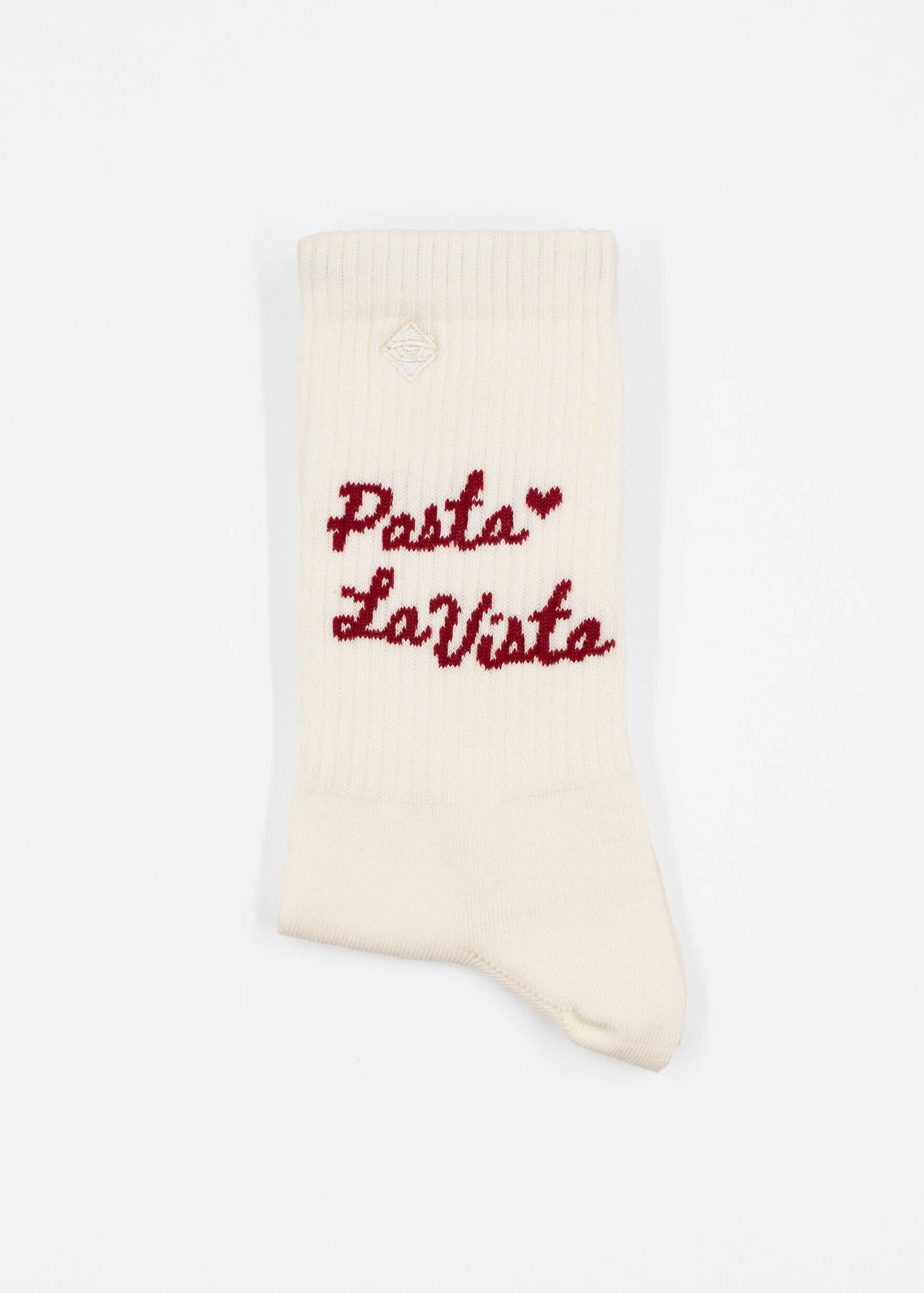 Eine cremefarbene J.Clay Tennissocke mit gerippter Struktur zeigt "Pasta La Vista" in roter Schreibschrift und ein kleines rotes Herz über dem Text vor einem schlichten weißen Hintergrund.