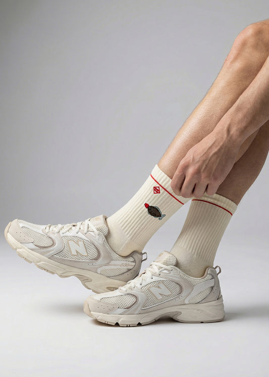 Person in weißen Turnschuhen und J.Clay Sushi Fish-Socken mit einem kleinen gestickten Cupcake.