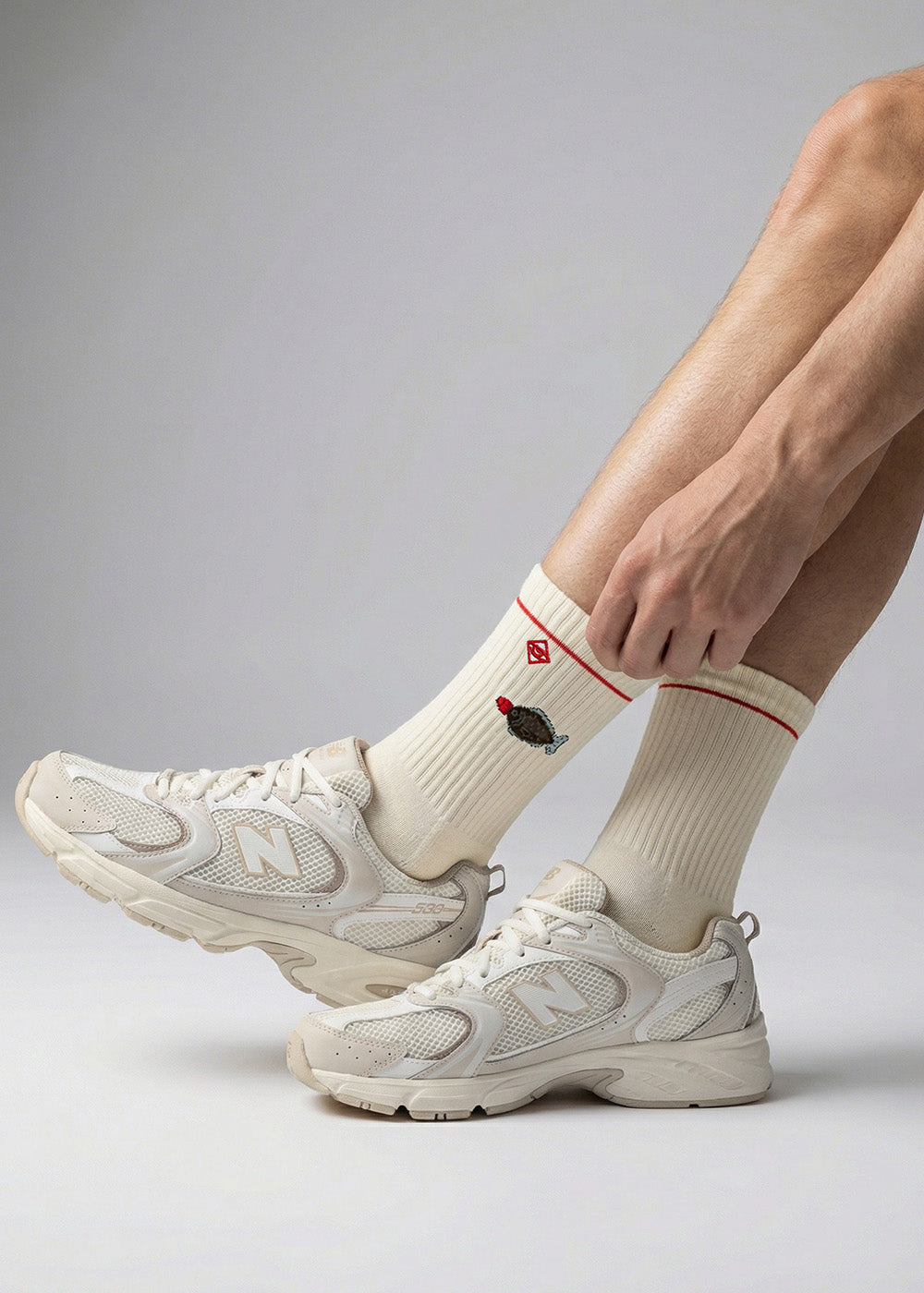 Person in weißen Turnschuhen und J.Clay Sushi Fish-Socken mit einem kleinen gestickten Cupcake.