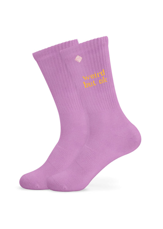 Ein Paar hellviolette Tennissocken von J.Clay mit gerippten Bündchen und gelber Stickerei "weird but ok" an den Seiten.