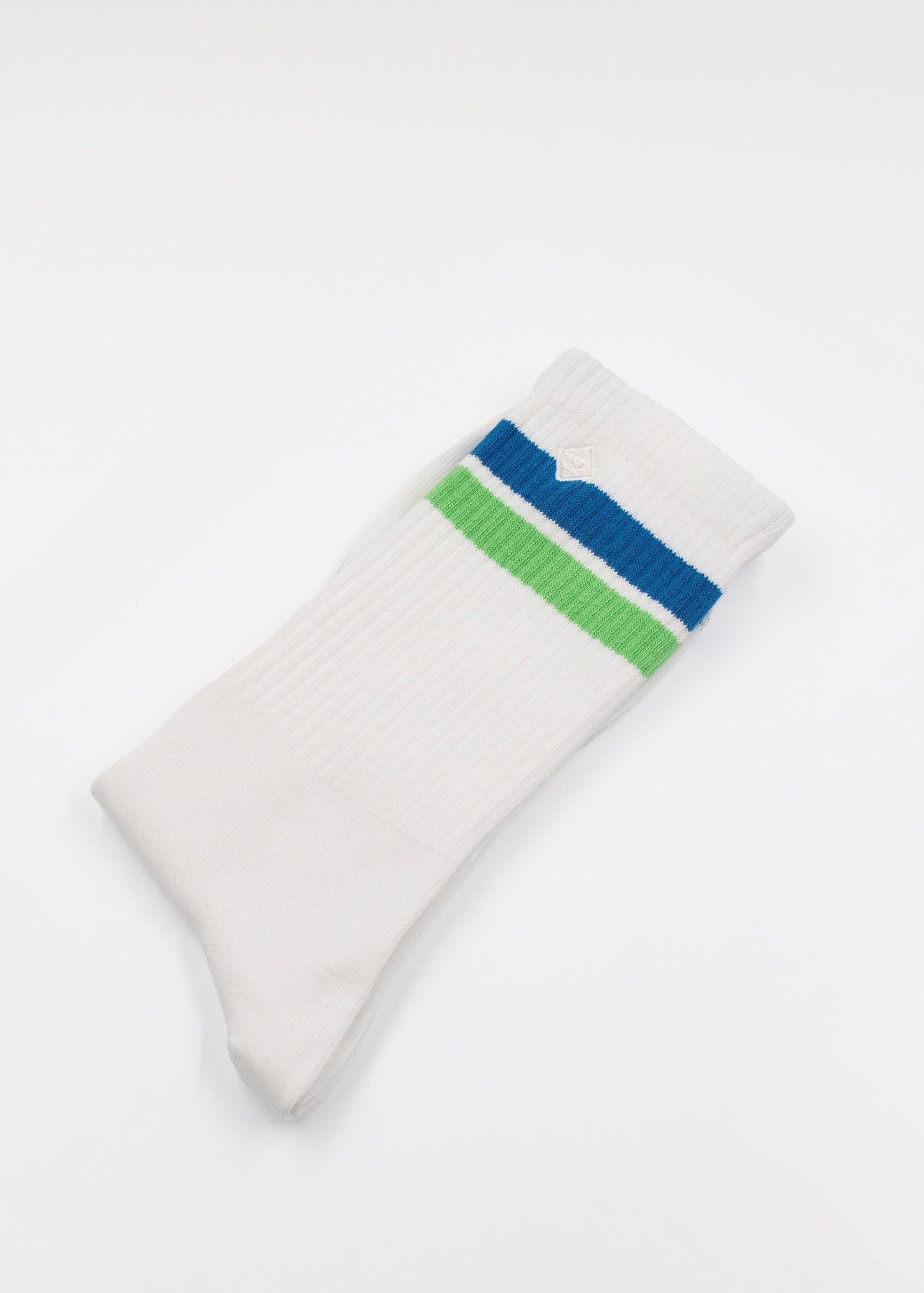 Ein einzelner weißer J.Clay Tennissocken mit geripptem Stoff und blaugrünen Querstreifen im oberen Bereich liegt flach auf einem einfarbig weißen Hintergrund.