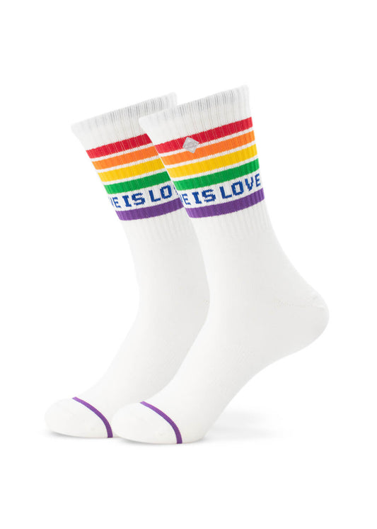 Ein Paar weiße J.Clay Tennissocken mit Regenbogenstreifen am oberen Rand, "LOVE IS LOVE" in lila Schrift und lila Akzenten an den Zehen und am Bündchen. Diese Crew-Socken sind vor einem schlichten weißen Hintergrund abgebildet.